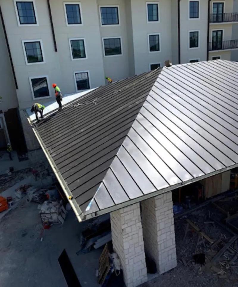 Crew installing standing seam metal roof panels on a commercial project in Covedale